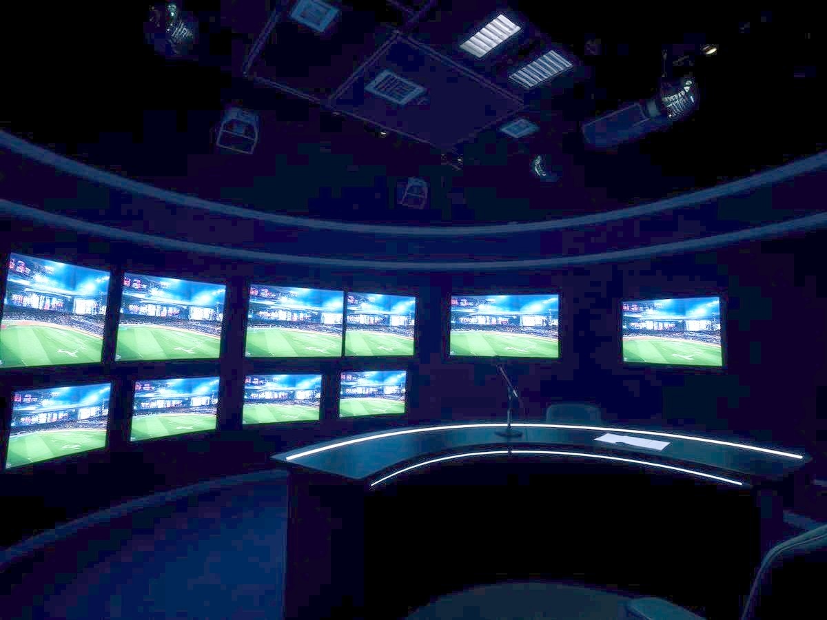 Darkened television sports studio with a bank of glowing monitors